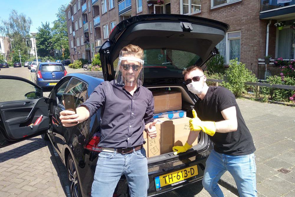 Two alumni loading packages into a car wearing PPE