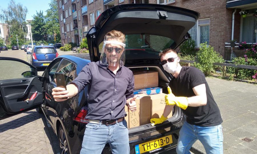 Two alumni loading packages into a car wearing PPE