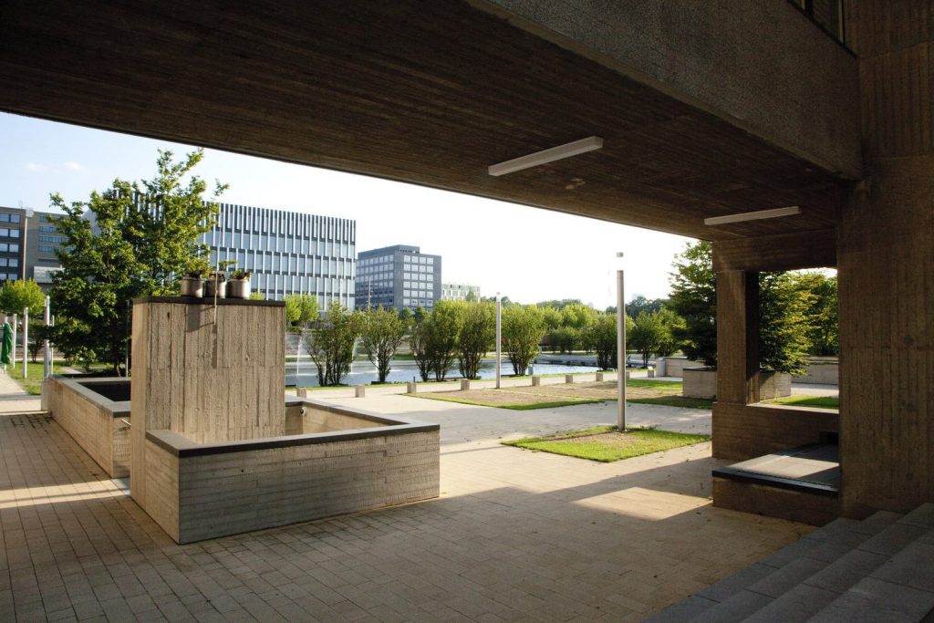 Summer picture of the lake on the EUR campus, with trees and shaded area of outdoor seating