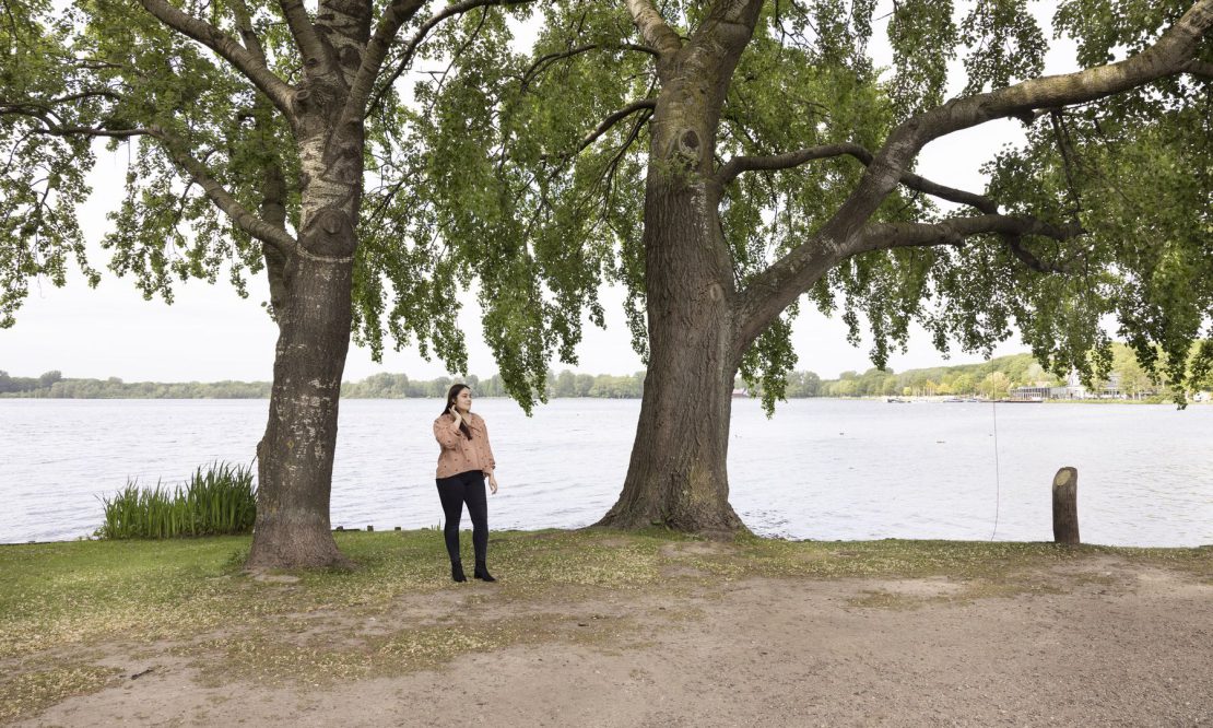 Ivona standing below trees with the lake behind her