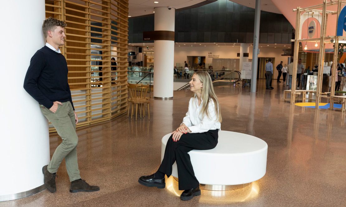 Lisa van Bekkum (FI, 2019) and Rutger Delhaas (FI, 2020) sit in the entrance lobby of Rabobank HQ in Utrecht