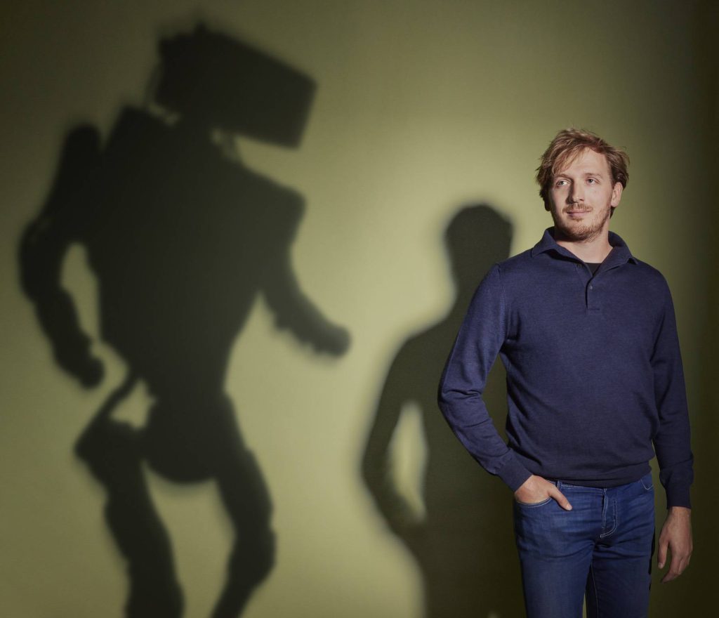A picture of a man with the shadow of a robot behind him